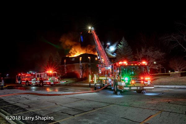 dramatic photo of fire trucks battling a fire at nighr