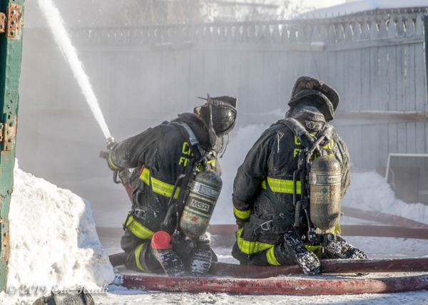 Firefighters with hose line at winter fire