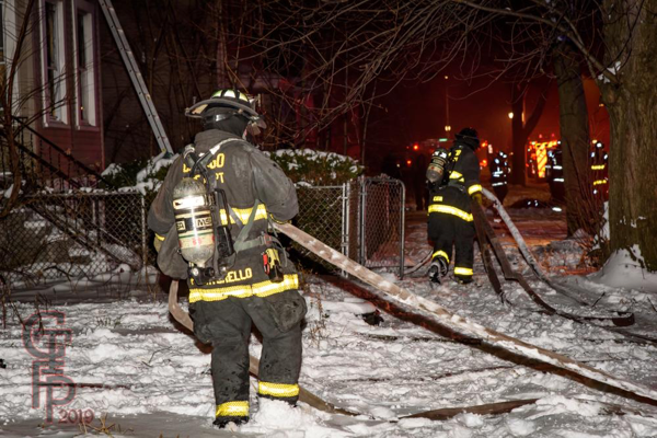 Firefighters pull attack line in the snow