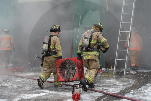 Firefighters carry smoke ejector at fire scene