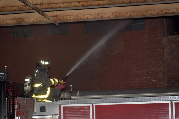Firefighter operates deck gun at fire scene