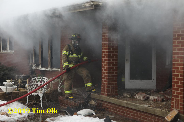 Firefighter holds hose at house fire