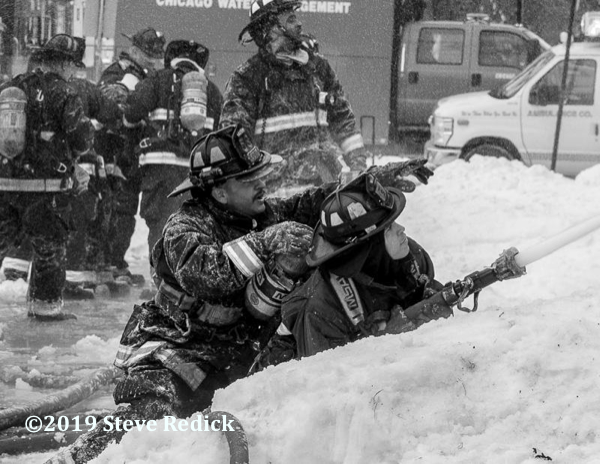 Firefighters with hose line in the snow