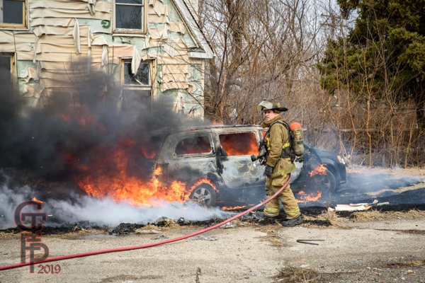 Firefighter prepares to extinguish a minivan destroyed by fire