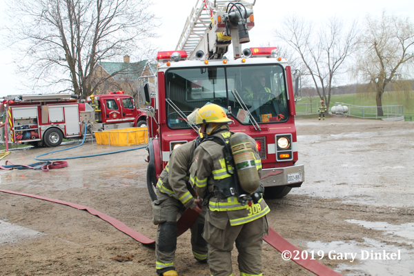 Firefighters connect hose at fire scene