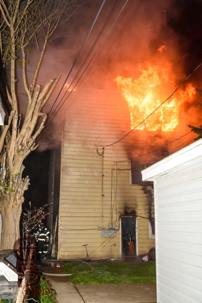 fire erupts from rear apartment window at night