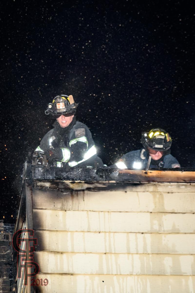 Firefighters om roof of fire building at night