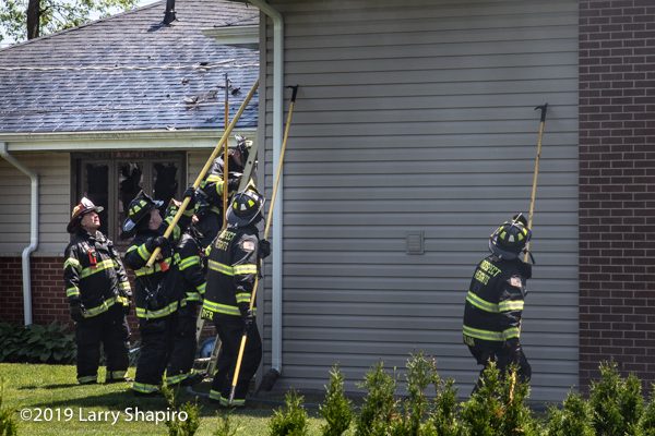Firefighters use four pike poles to pull soffits