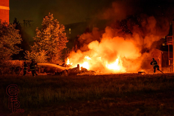 Firefighters extinguishing a pile of tires burning at night