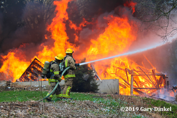Firefighters with hose battle flames