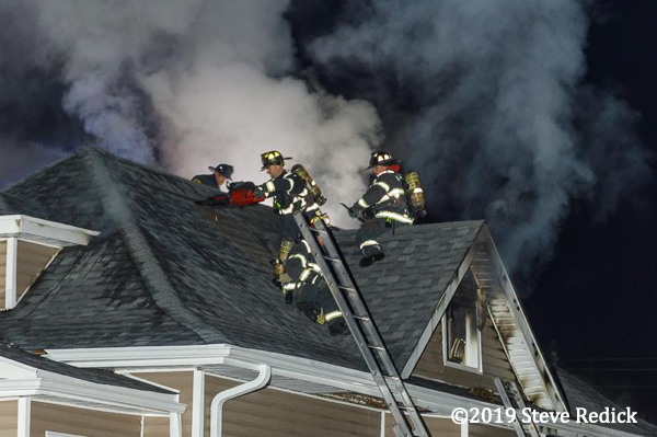Firefighters vent a roof at night