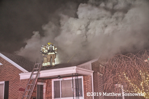 Firefighters on roof of house in smoke