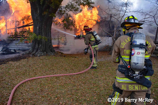 Firefighter with hose battles house fire
