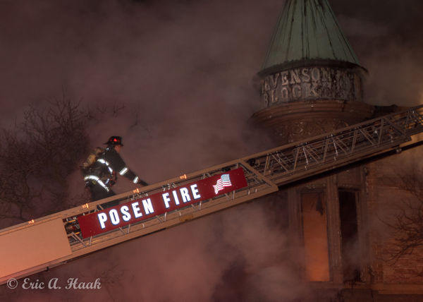 Firefighter climbs aerial ladder at night