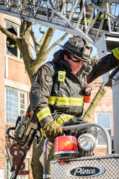 Firefighter in PPE carries power saw