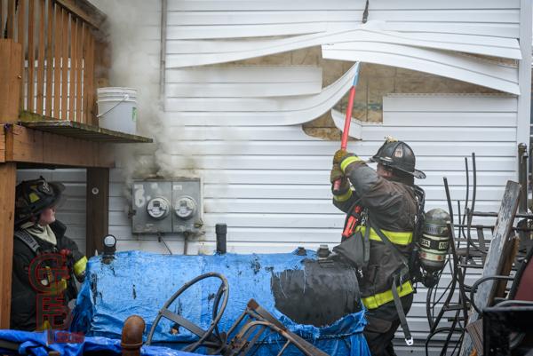 Firefighter pulls siding from house