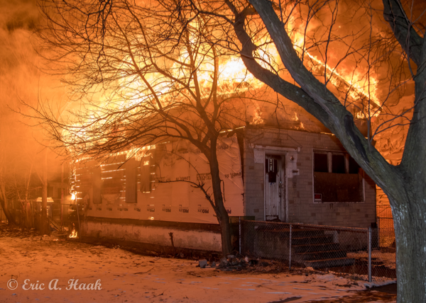 flames engulf the roof of a house at night
