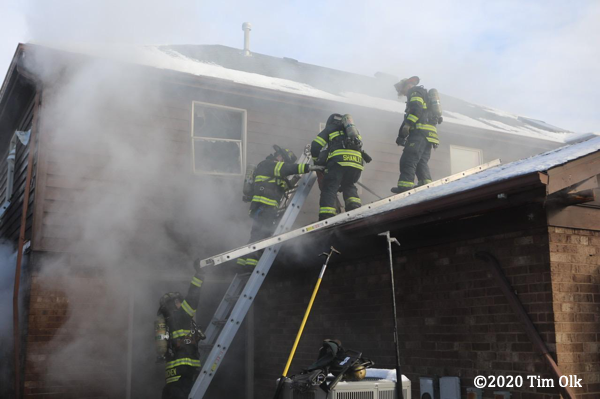 Firefighters on the roof of a house with snoe