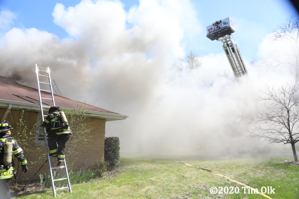 Firefighters climb ladder at house fire
