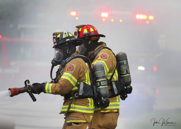 Firefighters in full PPE with hose line